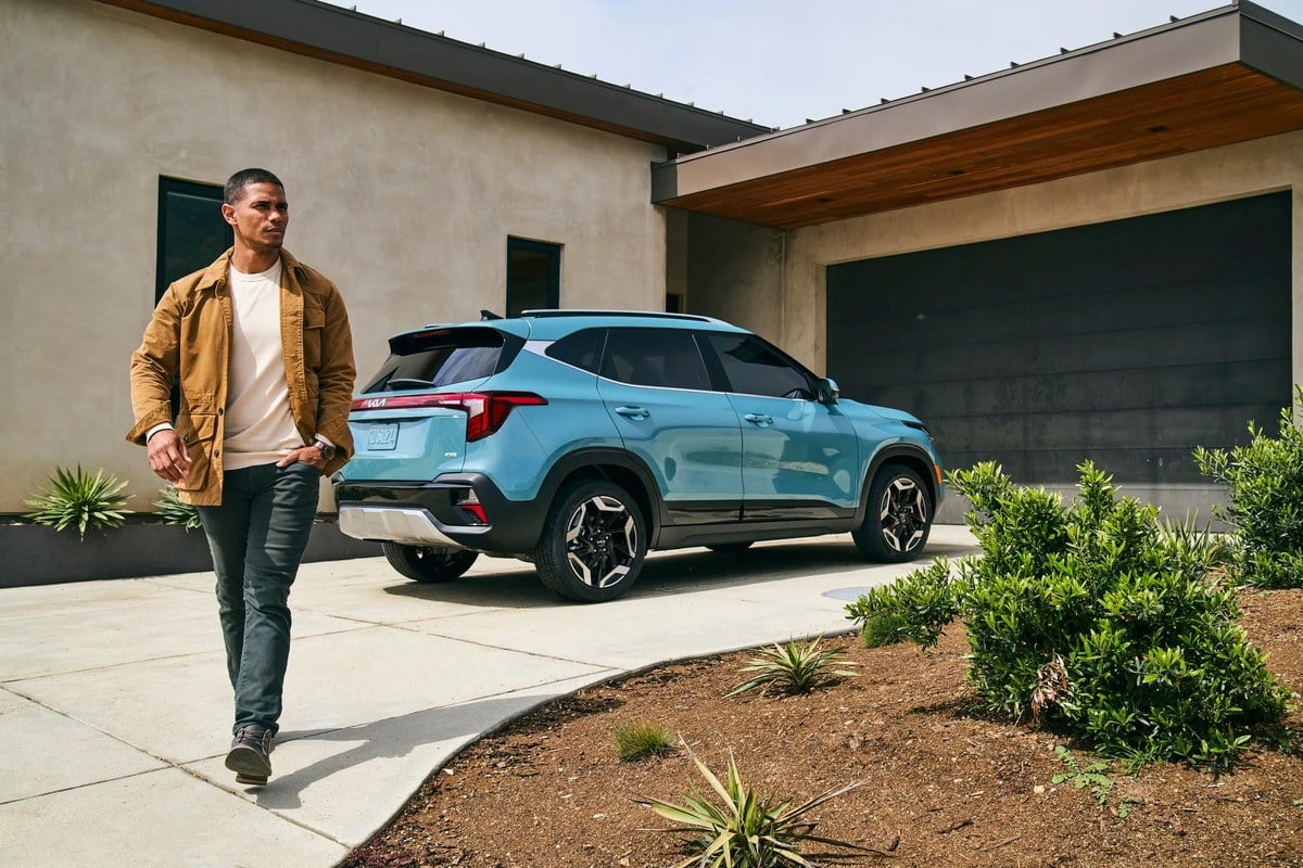 A new Kia Seltos on the driveway of a family home, a compact SUV sized for everyday driving