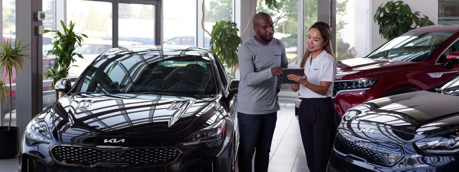 A Scarboro Kia product specialist going through options with a customer on the showroom floor in Scarborough, Ontario