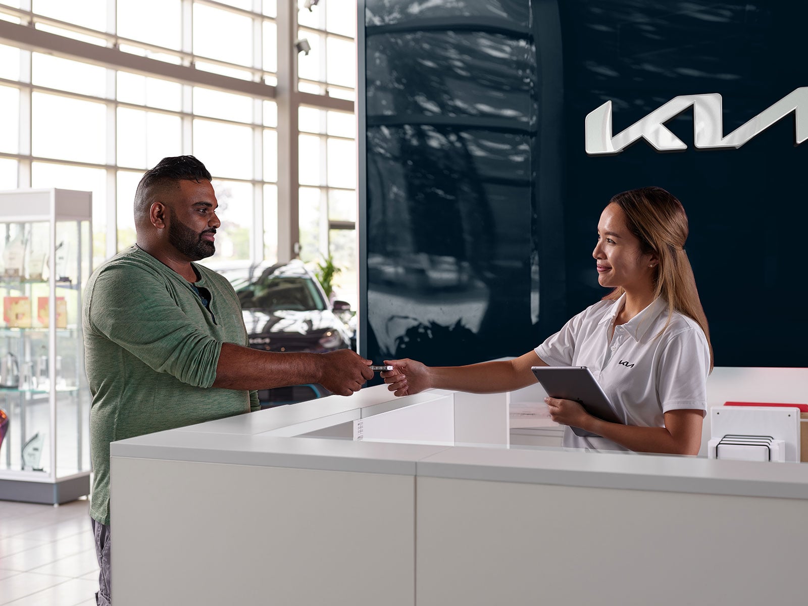 Keys handed across the front desk at Scarboro Kia on delivery day in Scarborough, Ontario